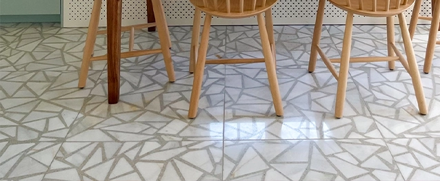 el suelo de un comedor decorado con triángulos de terrazo blanco y gris