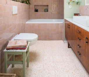 O chão da casa de banho é feito de terrazzo creme, bege e amarelo